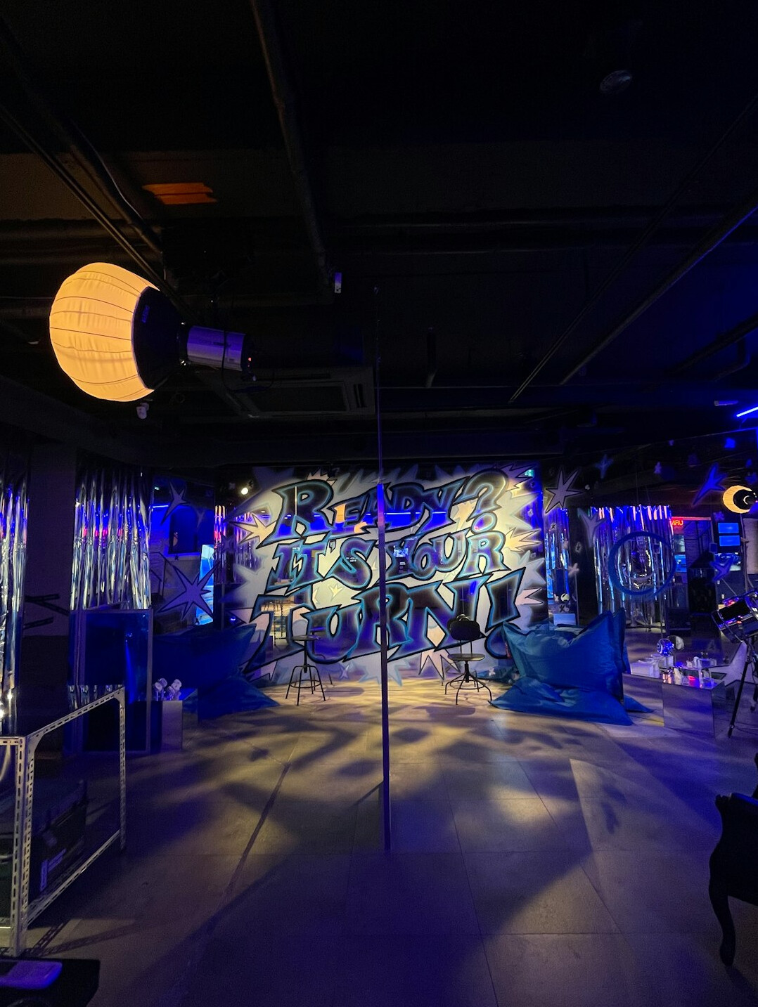 Studio lighting rig with LED panels and softboxes above a TV set